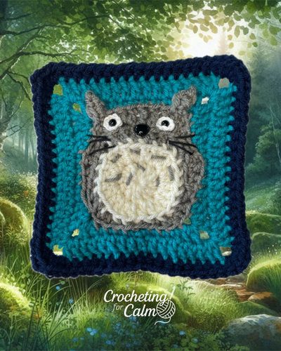 Teal crochet granny square featuring a gray and cream Totoro amigurumi-style applique with embroidered whiskers.