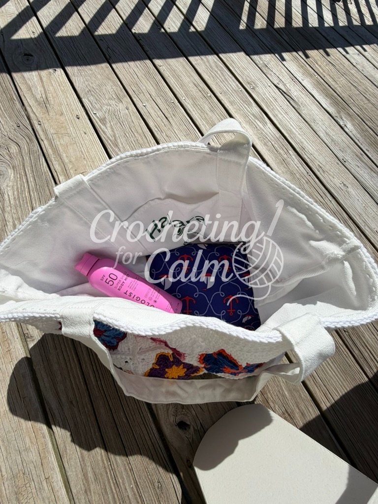 Inside view of a white crochet tote bag lined with a repurposed white canvas Halara bag, showing a pink sunscreen bottle and a blue nautical anchor-print fabric lining the bottom.