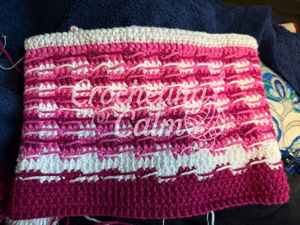Interior view of a pink, fuchsia, and white crochet pouch project showing carried yarn floating across the back of the stitches instead of being worked inside them.