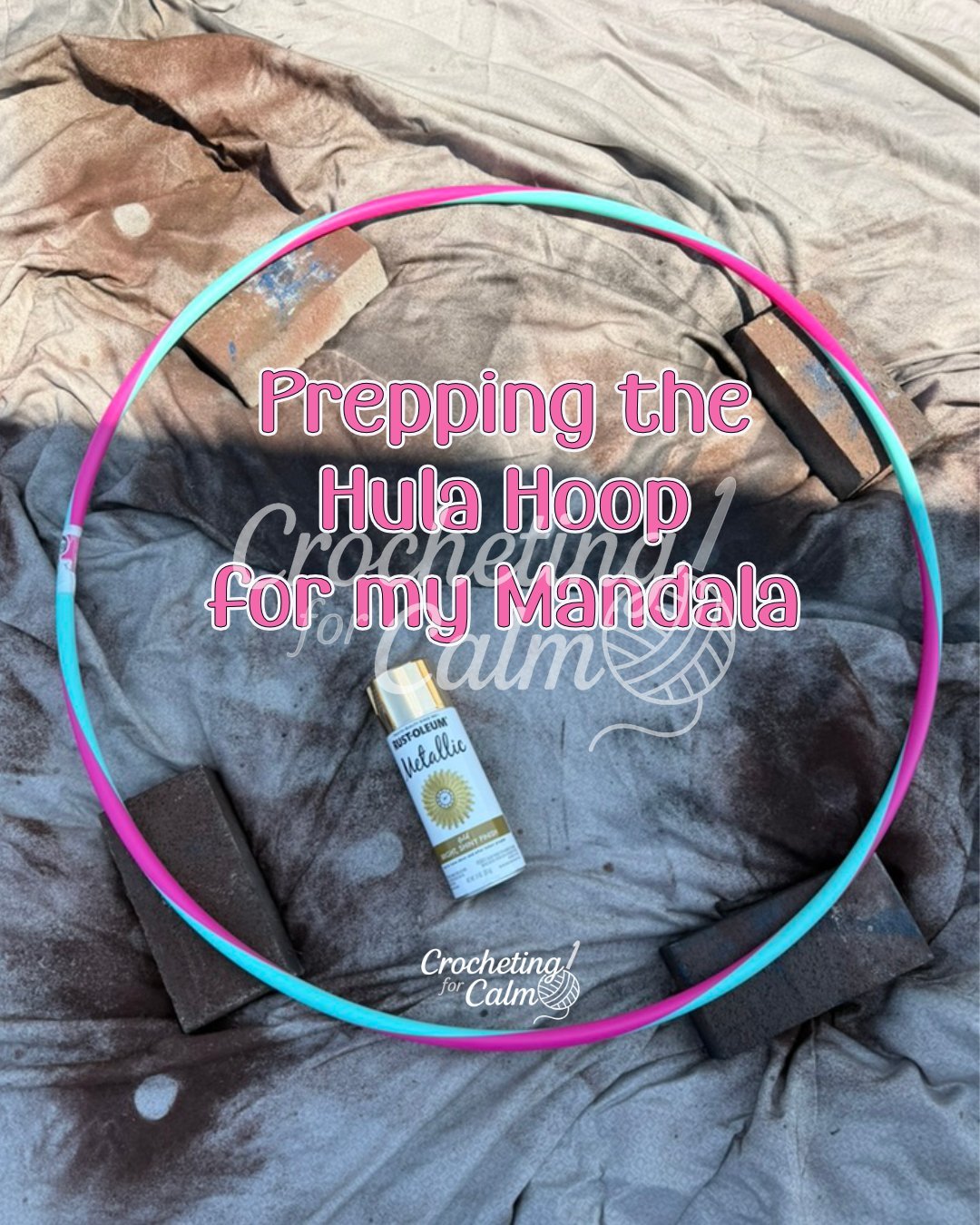 Pink and teal plastic hula hoop being prepped for a crochet mandala project, propped up on four bricks on a drop cloth with a can of gold metallic spray paint in the center and text overlay that reads "Prepping the Hula Hoop for my Mandala."