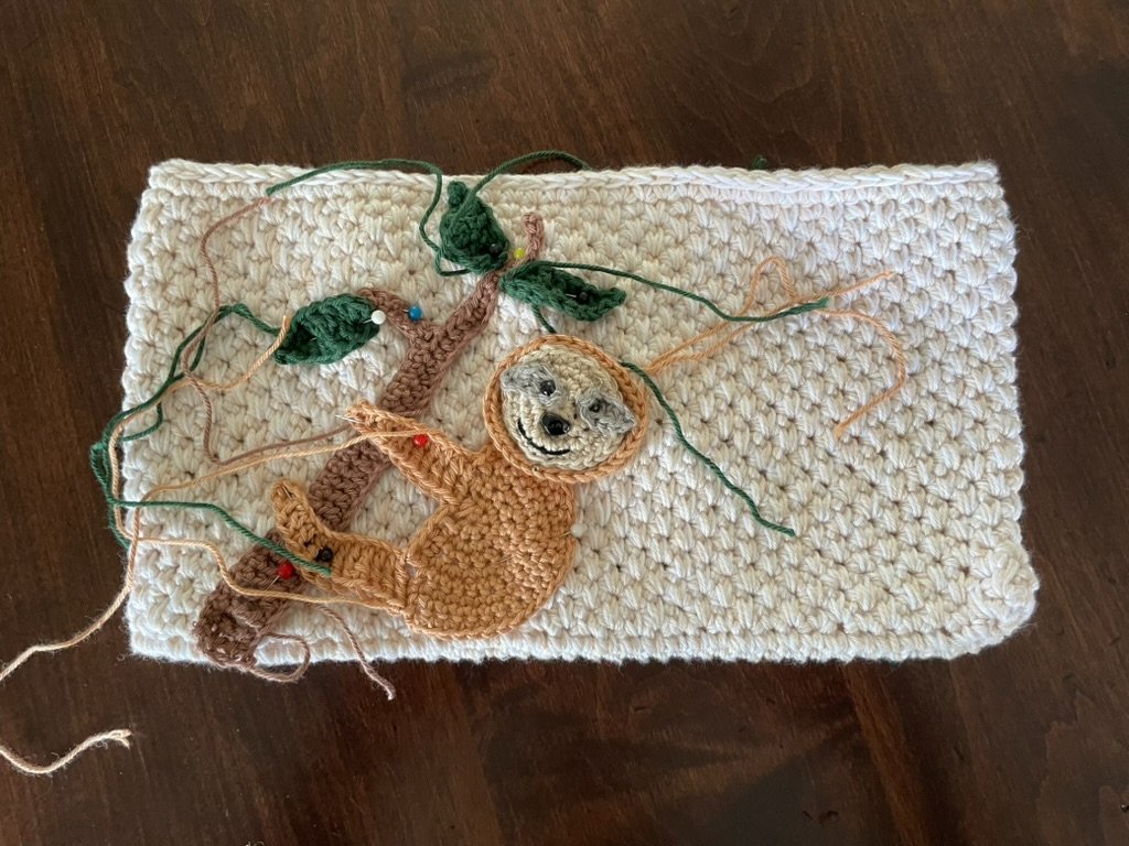 Sloth Zippered Crochet Bag - a work in progress showing the applique pinned to the bag before being sewn on.