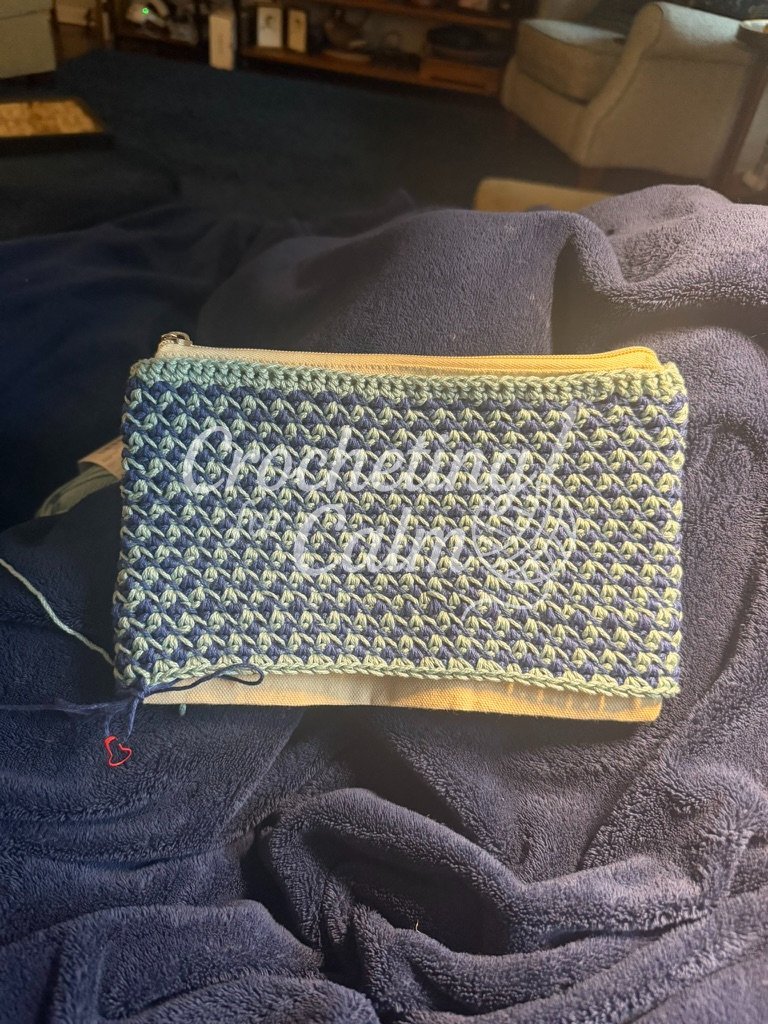In progress shot of Navy blue and light green geometric checkered crochet zippered pouch showing the zippered canvas pouch underneath.