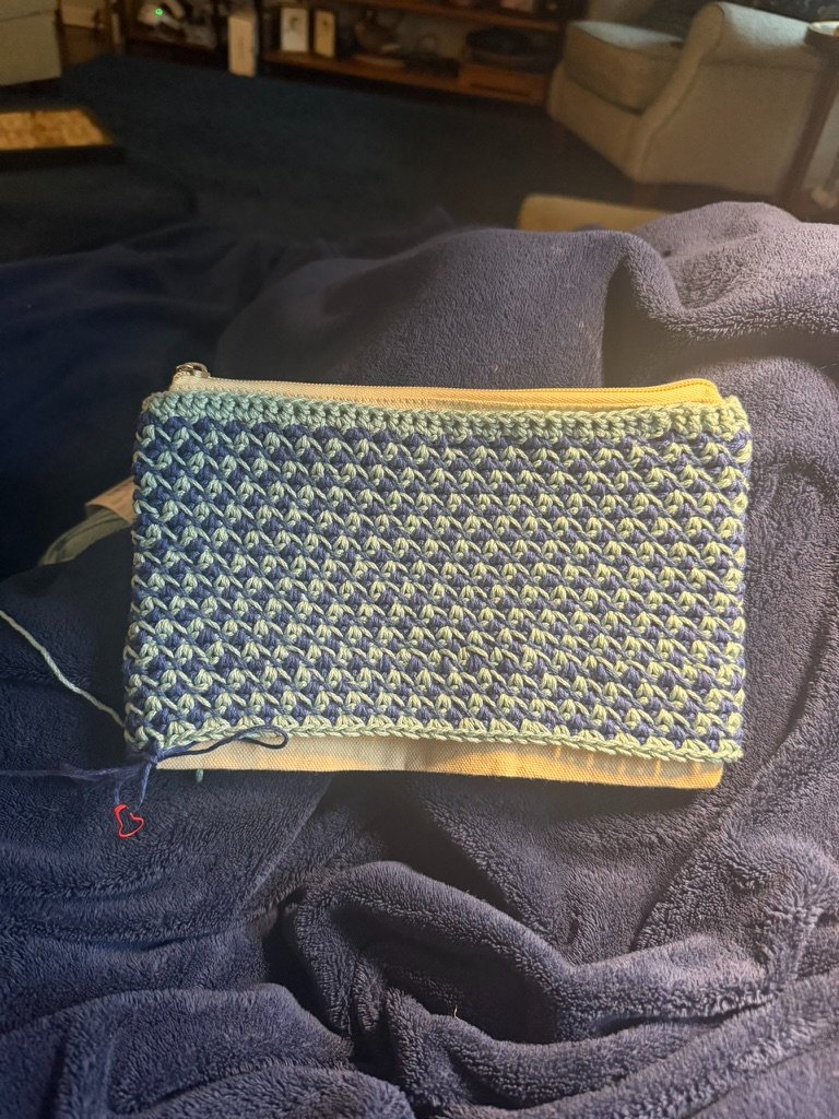 In progress shot of Navy blue and light green geometric checkered crochet zippered pouch showing the zippered canvas pouch underneath.