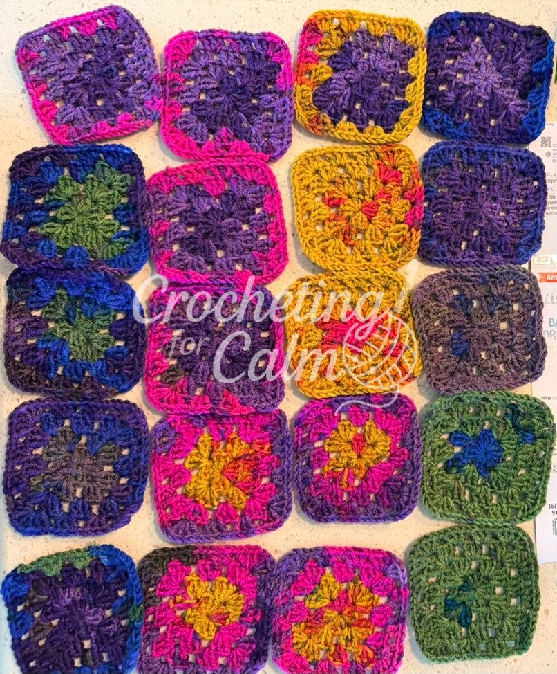 A grid flat lay showing twenty individual 3.5-inch multicolored granny squares arranged by shade and color progression.