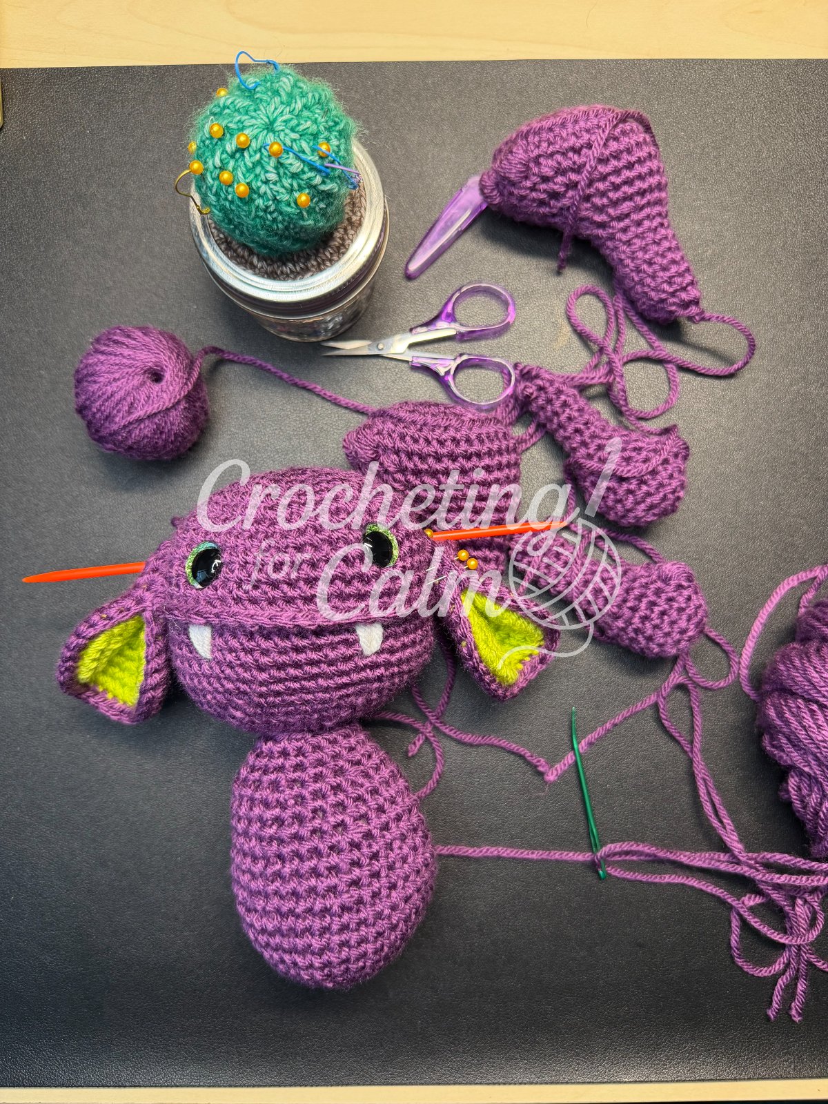 The Goblin Thing purple crochet goblin with bright green ears in the process of having its parts sewn together