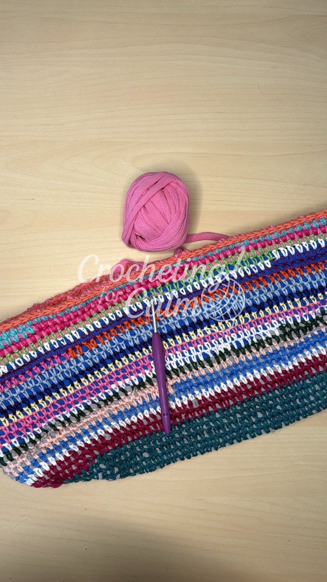 A scrap yarn tote bag in the process of being made. Shown with a 4mm crochet hook